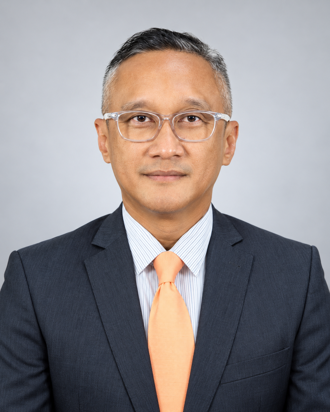 Norazly Basarian wearing a navy suit and orange tie
